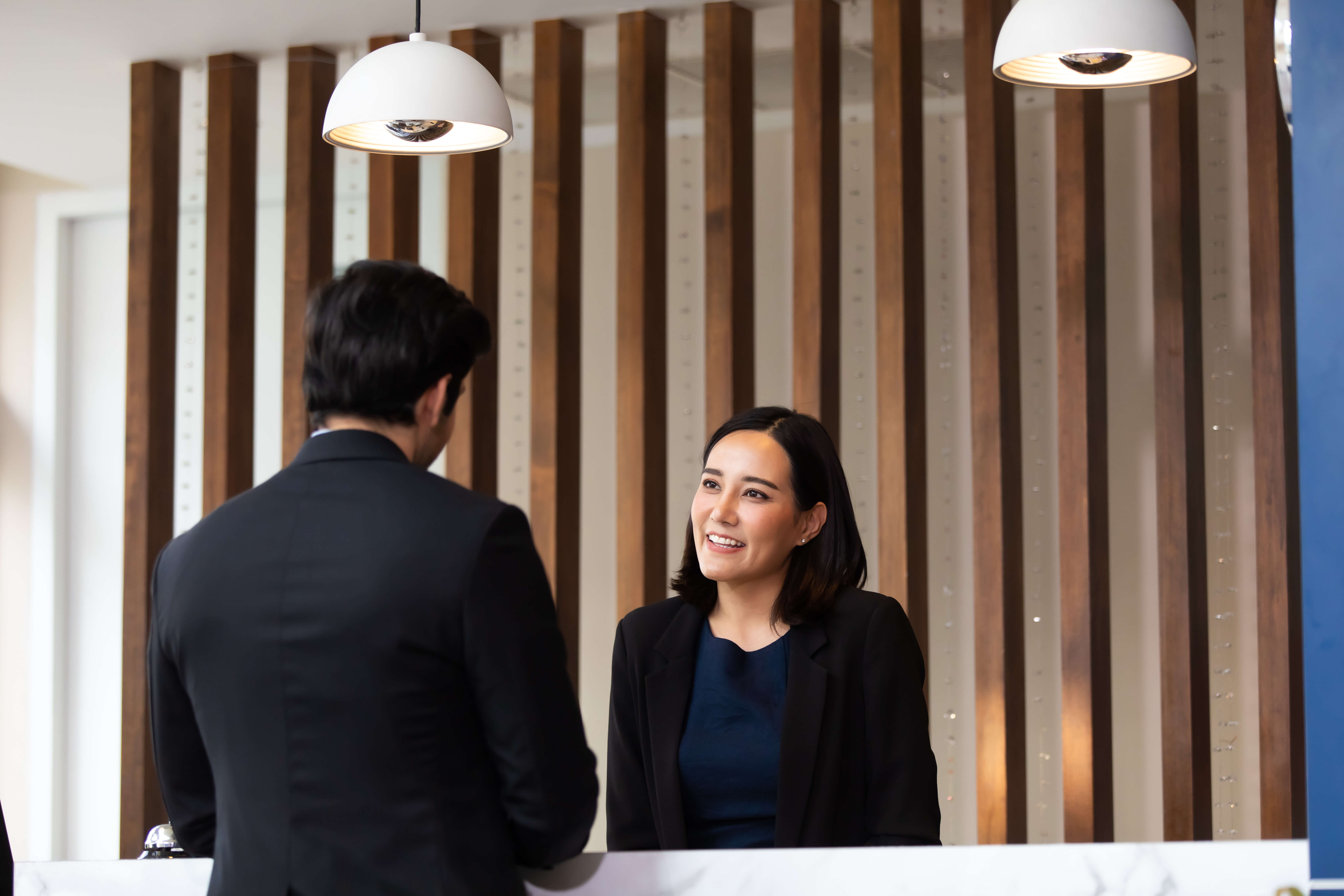 Przyjazna recepcjonistka pracująca przy biurku w hotelowym lobby. Wypoczynek i podróże podczas wakacji.